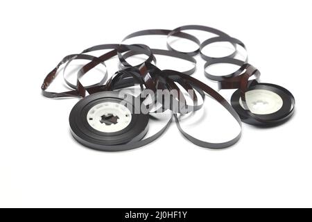 Alte Kassette mit aufgewickeltes Klebeband. Beschädigtes Datenträger für alte Tonaufnahmegeräte. Weißer Hintergrund. Stücke von einem alten Vintage-Kassettenband Stockfoto