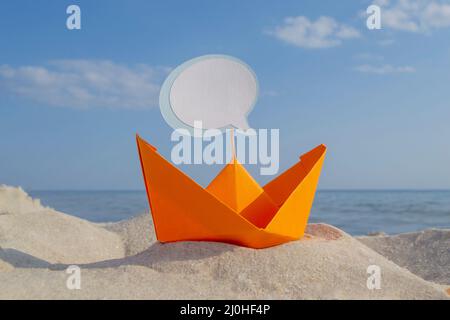 Orange Papier Boot auf Sandy Seashore Nahaufnahme kleines Boot aus Papier auf dem Hintergrund Stockfoto