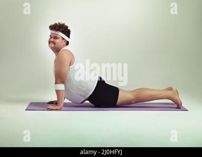 Diese nach oben gerichtete Hundehaltung ist großartig. Aufnahme eines übergewichtigen Mannes, der Yoga-Posen macht. Stockfoto