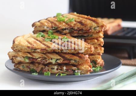 Sandwiches mit Frischkäse und Speck. Gegrillte Sandwiches mit einer Aufstrich aus einer Kombination aus Frischkäse, grünen Zwiebeln, Orangano und Chili Flocken. Schuss mit Witz Stockfoto