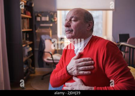 Älterer Mann, der zu Hause an schweren Schmerzen in seinem Brustherzanfall leidet. Ältere Herzkrankheit Stockfoto