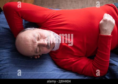 Ältere Mann schlafend auf dem Bett im Schlafzimmer zu Hause Stockfoto