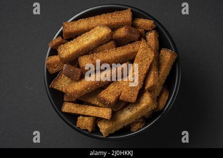 Schale aus Roggencroutons auf schwarzem Hintergrund Stockfoto