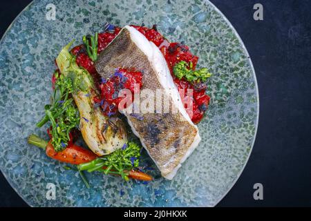 Traditionelles, gebratenes Kabeljaufischfilet im modernen Stil mit Fenchel und Tomatencreme, serviert von oben auf der Platte mit nordischem Design Stockfoto