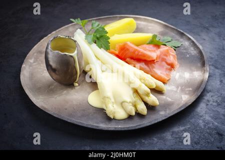 Traditioneller gedämpfter weißer Spargel mit geräucherten Lachsscheiben und gekochten Kartoffeln, garniert mit Sauce Hollandaise, serviert als Clo Stockfoto