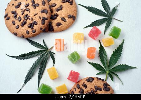 Marmelade und amerikanische Kekse mit Cannabisextrakt. Süßigkeiten mit CBD-Öl. Marihuana Blätter auf weißem Hintergrund. Draufsicht, flach liegend. Stockfoto
