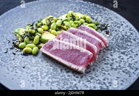 Traditionelles japanisches Gourmet-Steak Tataki mit Thunfisch und Avocado-Früchten und Edamame-Sojabohnen im modernen Stil, das als Nahestehende serviert wird Stockfoto