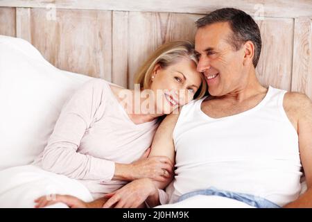 Lächelnde reife Frau, die auf der Schulter des Ehemanns ruht. Porträt einer lächelnden reifen Frau, die auf der Schulter des Ehemanns ruht. Stockfoto