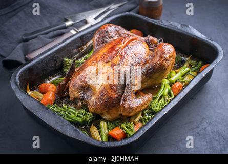 Traditionelles Grillhähnchen mit Baby-Brokkoli und Karotten diente als Nahaufnahme in einem alten rustikalen Metalltablett Stockfoto