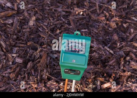 3 in 1 Leuchtdichte Feuchtigkeit und pH-Meter, die den Zustand des Bodens in der Grenze mit Mulch gefüllt ist, ist ziemlich nass. Stockfoto