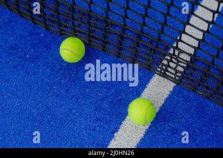Zwei Paddle-Tennisbälle über der Service-Linie und in der Nähe des Netzes eines blauen Paddle-Tennisplatzes Stockfoto