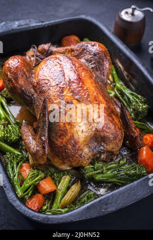 Traditionelles Grillhähnchen mit Baby-Brokkoli und Karotten diente als Nahaufnahme in einem alten rustikalen Metalltablett Stockfoto