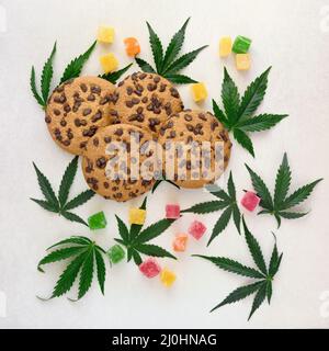 Amerikanische Cookies mit Cannabisextrakt. Süßigkeiten mit CBD-Öl. Marihuana Blätter auf weißem Hintergrund. Draufsicht, flach liegend. Stockfoto