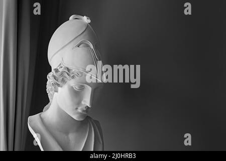 Statue der antiken griechischen Göttin Athene Pallas auf dunklem Hintergrund mit Copyspace. Marmorne Frauenkopf in Helmskulptur Stockfoto