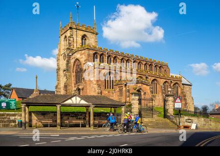 Fahrradfahrer hielten vor der Pfarrkirche St. Jakob dem Großen im Cheshire-Dorf Audlem an, um sich zu erholen. Stockfoto