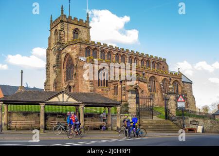 Fahrradfahrer hielten vor der Pfarrkirche St. Jakob dem Großen im Cheshire-Dorf Audlem an, um sich zu erholen. Stockfoto