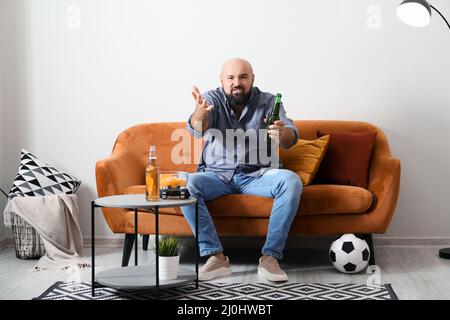 Lustiger fauler Mann, der zu Hause Bier trinkt und Fußball gucken kann Stockfoto