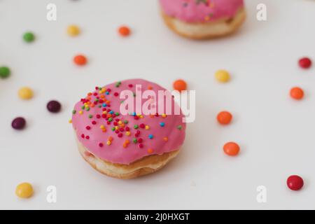 Urlaub, Geburtstagsfeier Komposition mit bunten rosa glasierten Donuts auf weiß. Stockfoto