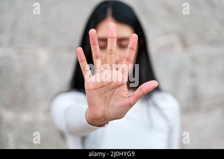 Frau hebt ihre Hand, um zu sagen, dass genug genug ist. Kampagne zur Beendigung der Gewalt gegen Frauen. Latina Frau mit der Hand, die ihr Gesicht bedeckt Stockfoto