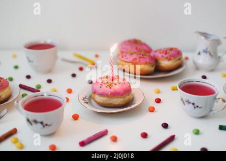 Urlaub, Geburtstagsfeier Komposition mit bunt rosa glasierten Donuts auf weißem Tisch, Flatlay Draufsicht. Stockfoto