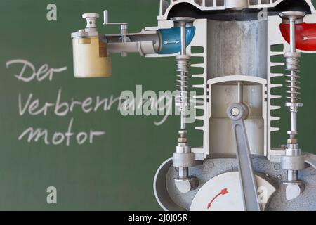 Schnittmodell eines Verbrennungsmotors mit einer Tafel im Hintergrund und deutschem Text Stockfoto