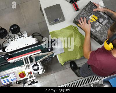 Arbeiter, der ein Paket für den Versand in einer Brauerei vorbereitet Stockfoto