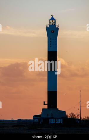 DUNGENESS, KENT, Großbritannien - FEBRUAR 3 : Sonnenuntergang hinter dem Leuchtturm am Strand von Dungeness in Kent am 3. Februar 2008 Stockfoto