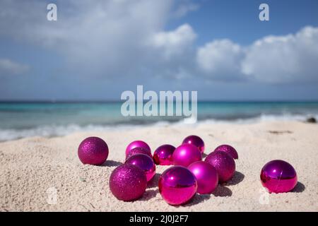 Rosa Weihnachtskugeln am Strand. Weihnachten in den Tropen. Selektiver Fokus Stockfoto