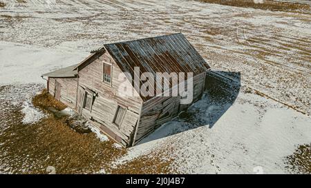 Ein Gebäude, das unter seinem eigenen Gewicht zusammenbricht, während Schnee um es schmilzt Stockfoto