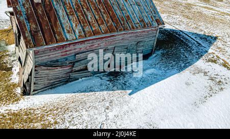 Ein Gebäude, das unter seinem eigenen Gewicht zusammenbricht, während Schnee um es schmilzt Stockfoto