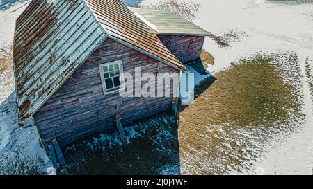 Ein Gebäude, das unter seinem eigenen Gewicht zusammenbricht, während Schnee um es schmilzt Stockfoto