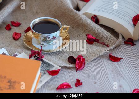 Turkısh Kaffee in klassischer Tasse, Holzhintergrund mit romantischen Rosenblättern, Buch über Liebe unter alten Vintage-Bildern, mit beige Farbe schmücken. Stockfoto