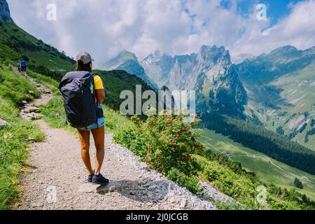 Eine Frau mit einem Rucksack steht auf einem Berg, das Mädchen reist an schöne Orte, das Ziel zu erreichen, Bergrücken an Stockfoto