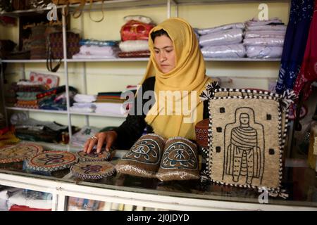 Bamiyan, Afghanistan. 19. März 2022. Am 19. März 2022 erwartet eine afghanische Frau am Art Bazaar in Bamiyan, Zentralafghan, Kunden. Quelle: Saifurahman Safi/Xinhua/Alamy Live News Stockfoto