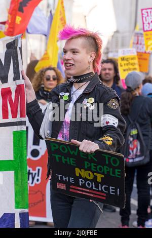 Anti-Rassismus-Protest auf den Straßen von London. Ein Protestor mit pinkfarbenem Haarschnitt im Punk-Stil, der ein Banner hält. London - 19.. März 2022 Stockfoto