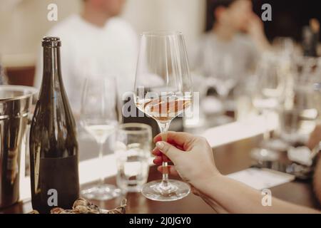 Gläser mit verschiedenen Weinsorten und menschlichen Händen, die Weingläser im Hintergrund halten Stockfoto