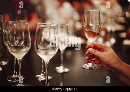 Gläser mit verschiedenen Weinsorten und menschlichen Händen, die Weingläser im Hintergrund halten Stockfoto