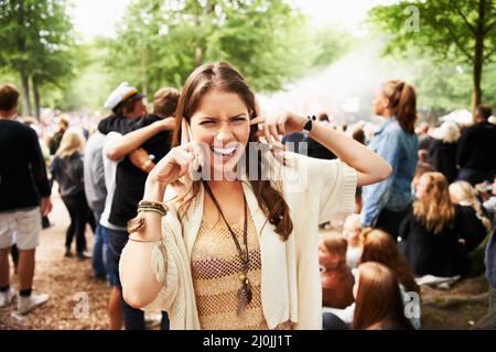 Ich kann dich nicht hören. Eine junge Frau, die auf einem Festival im Freien schwer mit ihrem Smartphone zu hören ist. Stockfoto