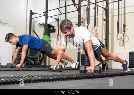 Zwei starke Männer, die Liegestütze im Fitnessstudio machen. Stockfoto