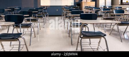 Ein leeres Klassenzimmer mit Schülertischen, die zur sozialen Distanzierung angeordnet sind. Stockfoto