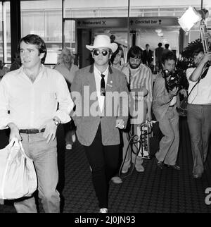 Mit einem stetson-Hut bekleidet verlässt Elton John den Flughafen Heathrow nach Amerika. Auf der linken Seite ist John Reid, der Manager von Elton. 10.. August 1980. Stockfoto