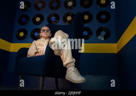 Porträt von stilvollen Teenager-Mädchen auf einem blauen Stuhl. Stockfoto