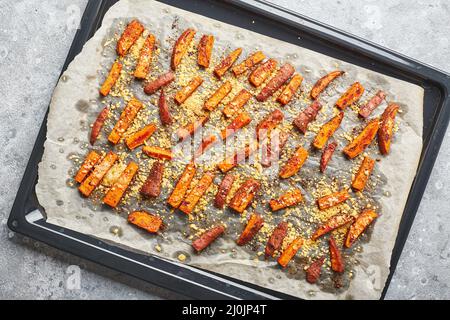 Süßkartoffel mit Käse auf Backblech auf grauem Hintergrund Stockfoto