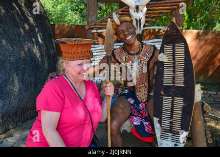 Zulu Stammesangehörige mit Tourist am Sun City Resort, Pilanesberg, Motseng Cultural Village, North West Province, Südafrika Stockfoto