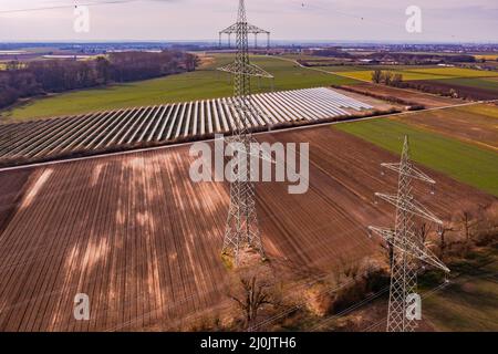 Technologie in landwirtschaftlichen Gebieten entstellt die Natur mit Strommasten und Freiflächen-Solaranlagen, Deutschland Stockfoto