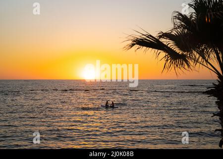 Zwei Frauen teilen sich das Paddelbrett bei Sonnenuntergang auf ruhigen Gewässern im mittelmeer in zypern. Zwei Mädchen paddeln auf SUP. Silhütte Stockfoto