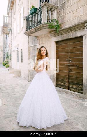 Die Braut im zarten Brautkleid steht in der Nähe von schönen alten Gebäude in Perast Stockfoto