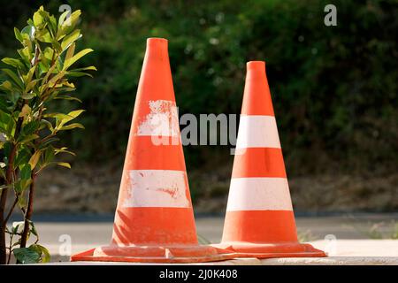 Orangefarbene Verkehrskegel stehen in einer Linie auf dem Asphalt, Nahaufnahme. Stockfoto