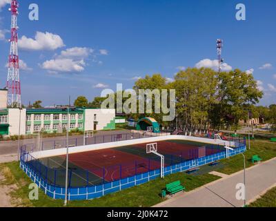 Sportplatz gegen Gebäude und Telekommunikationstürme unter bewölktem Himmel Stockfoto