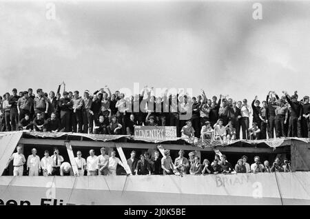 QE2 kehrt nach Southampton zurück. Union Jacks sind auf Autos festooniert, auf Schultern drapiert, auf Stöcken gewellt. Southampton begrüßt den Luxusliner aus dem Jahr QE2, der zum Trooper wurde und aus dem Krieg zurückkehrt, mit einem „Three Cheers“. An Bord ist ihre kostbare Fracht, die 700 Überlebenden der HMS Coventry, Ardent und Antelope, im Kampf um die Falklands versunken. 11.. Juni 1982. Stockfoto